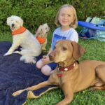 Kind mit drei Hunden am Boden sitzend